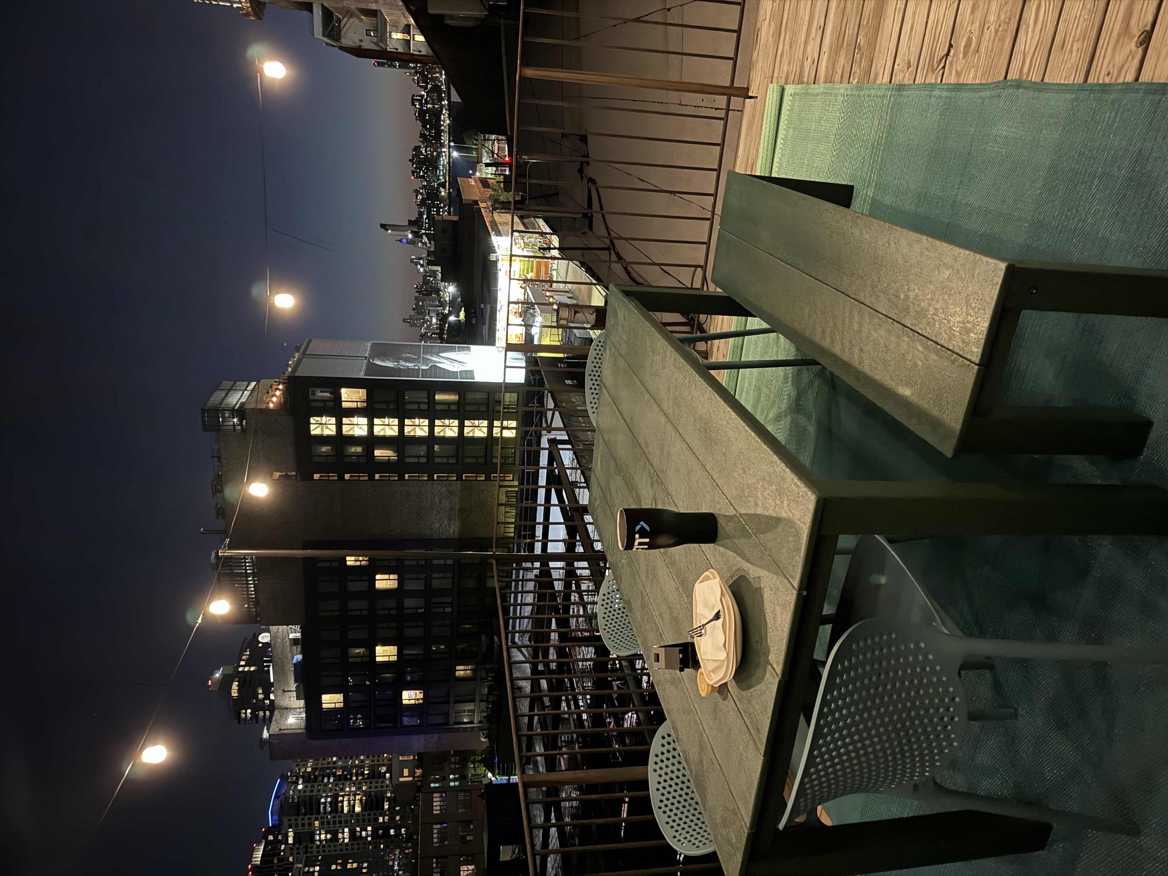Private terrace at night with string lights, a large dining table, and the Manhattan skyline glowing beyond